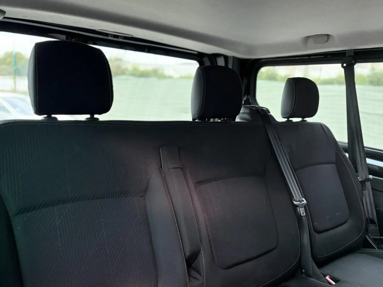 Vue rapprochée sur la banquette arrière noire du Nissan Primastar Combi 2025 avec appuie-têtes et ceintures visibles.