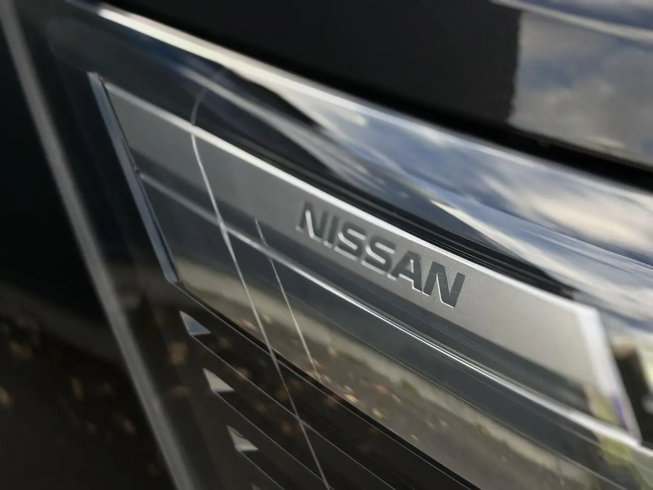 Gros plan sur la calandre noire métallisée du Nissan Primastar Combi 2025 avec logo Nissan argenté visible.