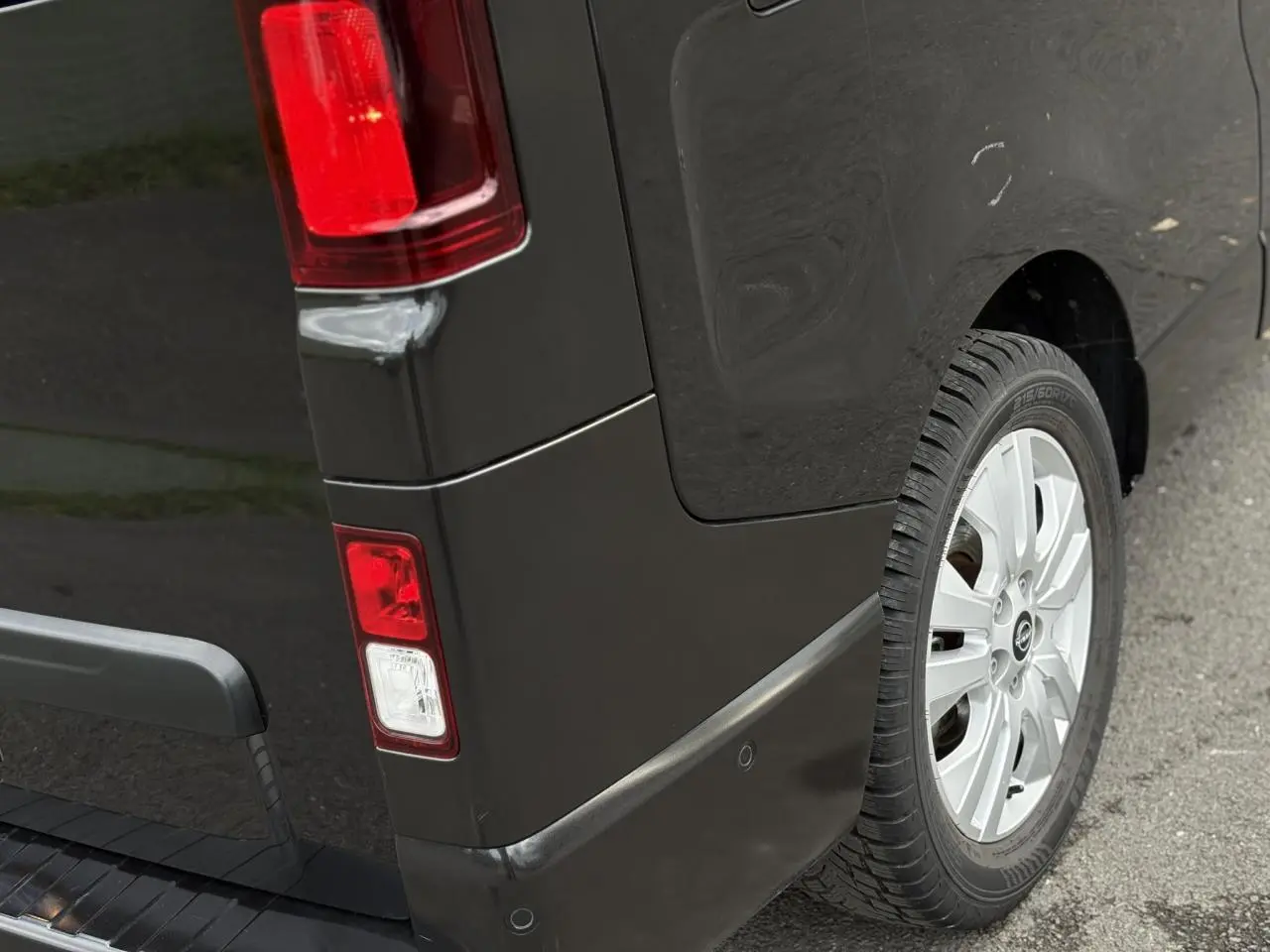Gros plan sur l'arrière droit noir métallisé du Nissan Primastar Combi avec feu arrière et jante alliage 17 pouces.