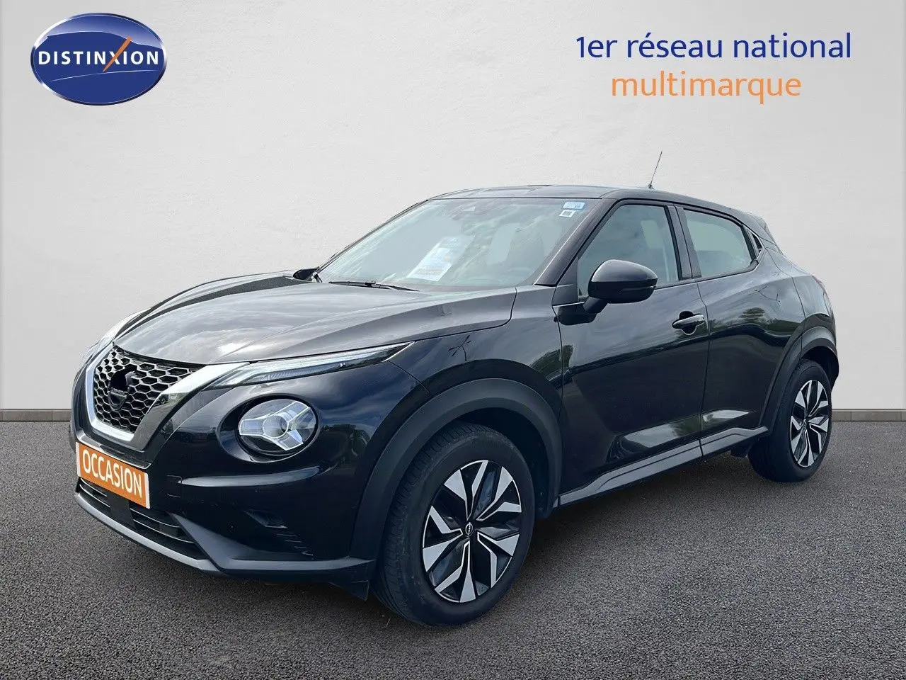 Nissan Juke noir métal en 3/4 avant droit, avec jantes distinctives et calandre en V caractéristique.