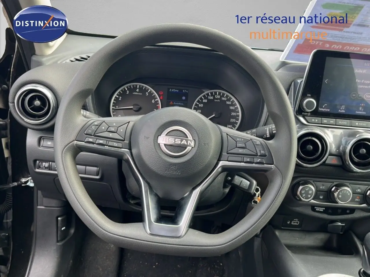 Vue intérieure centrée sur le volant Nissan du Juke 2023, avec tableau de bord et écran tactile visibles.
