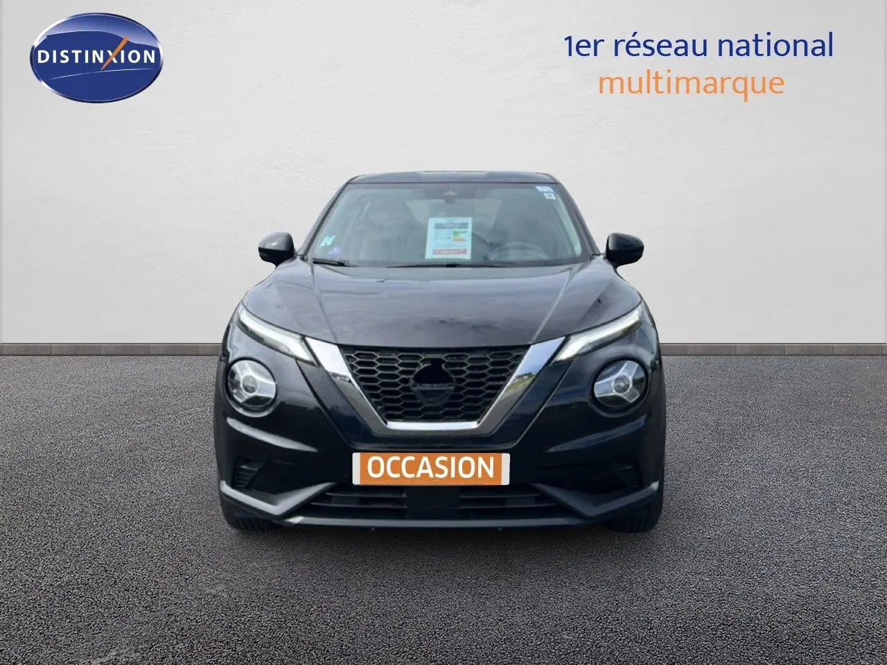 Vue avant d'un Nissan Juke noir métal 2023 avec calandre en V chromée et phares ronds distinctifs.