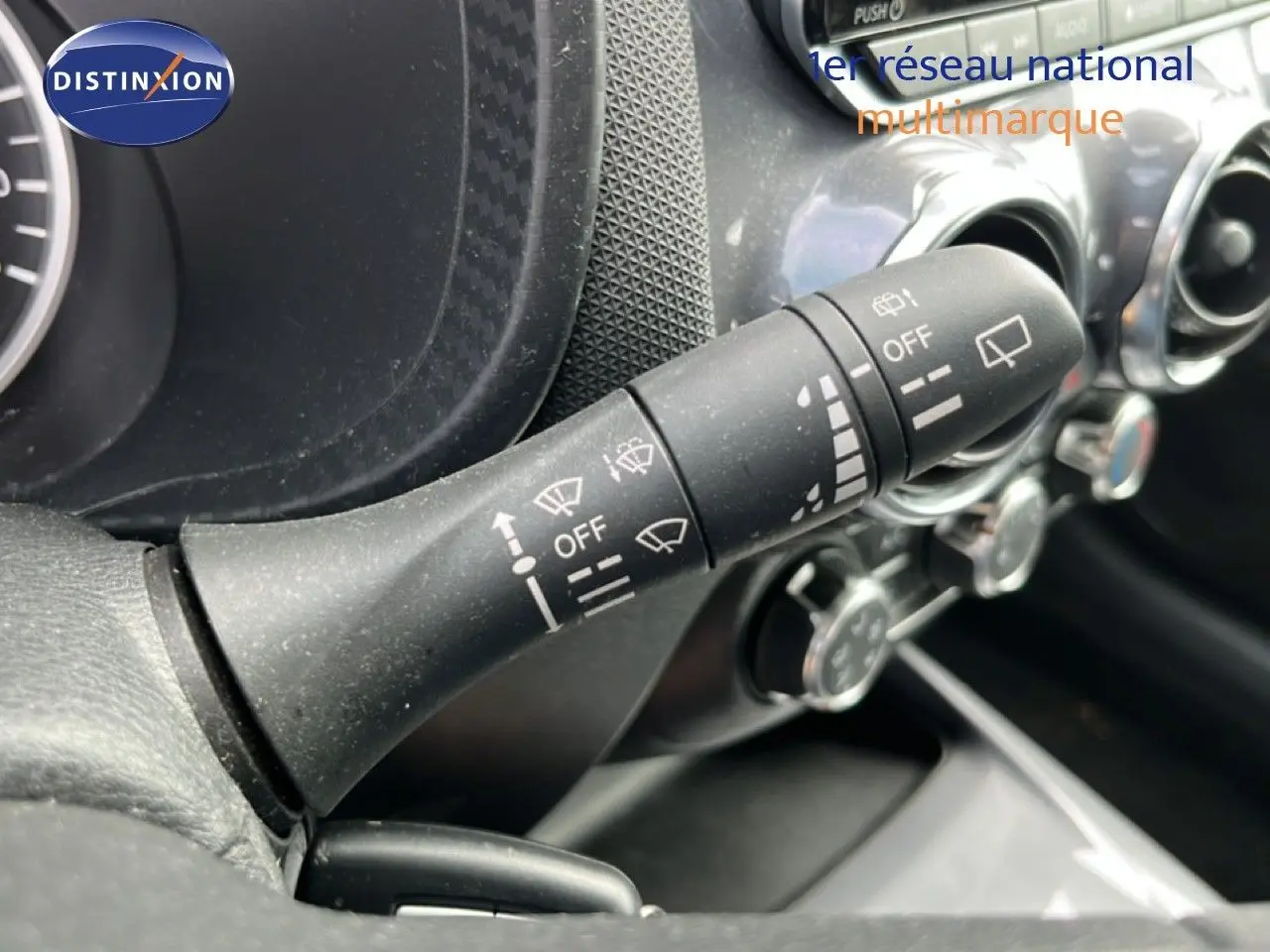 Gros plan sur la commande d’essuie-glace noire dans l’habitacle du Nissan Juke 2023, avec tableau de bord partiellement visible.