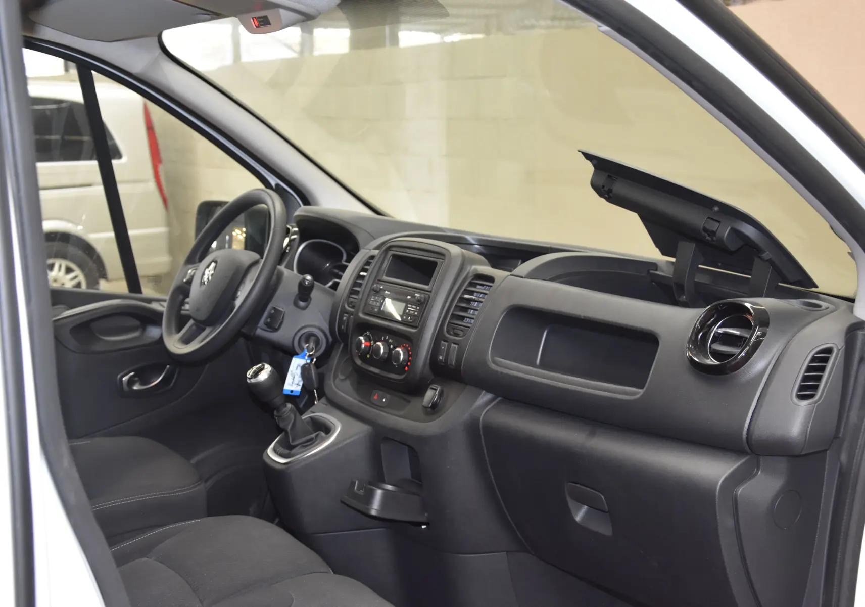 Vue intérieure côté conducteur du Renault Trafic Combi blanc 2021, volant multifonction et levier de vitesses manuelle visibles.