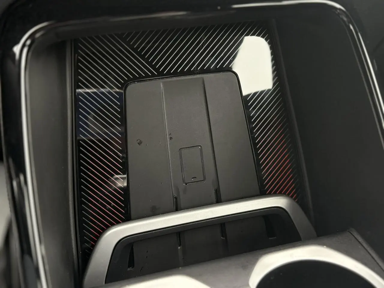 Gros plan sur la dalle de recharge par induction noire avec cadre argenté dans le BMW X1 blanc Mineral 2025.