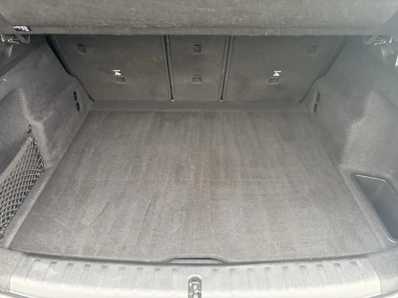 Vue intérieure du coffre spacieux et propre du BMW X1 blanc Mineral 2025, avec revêtement gris foncé.
