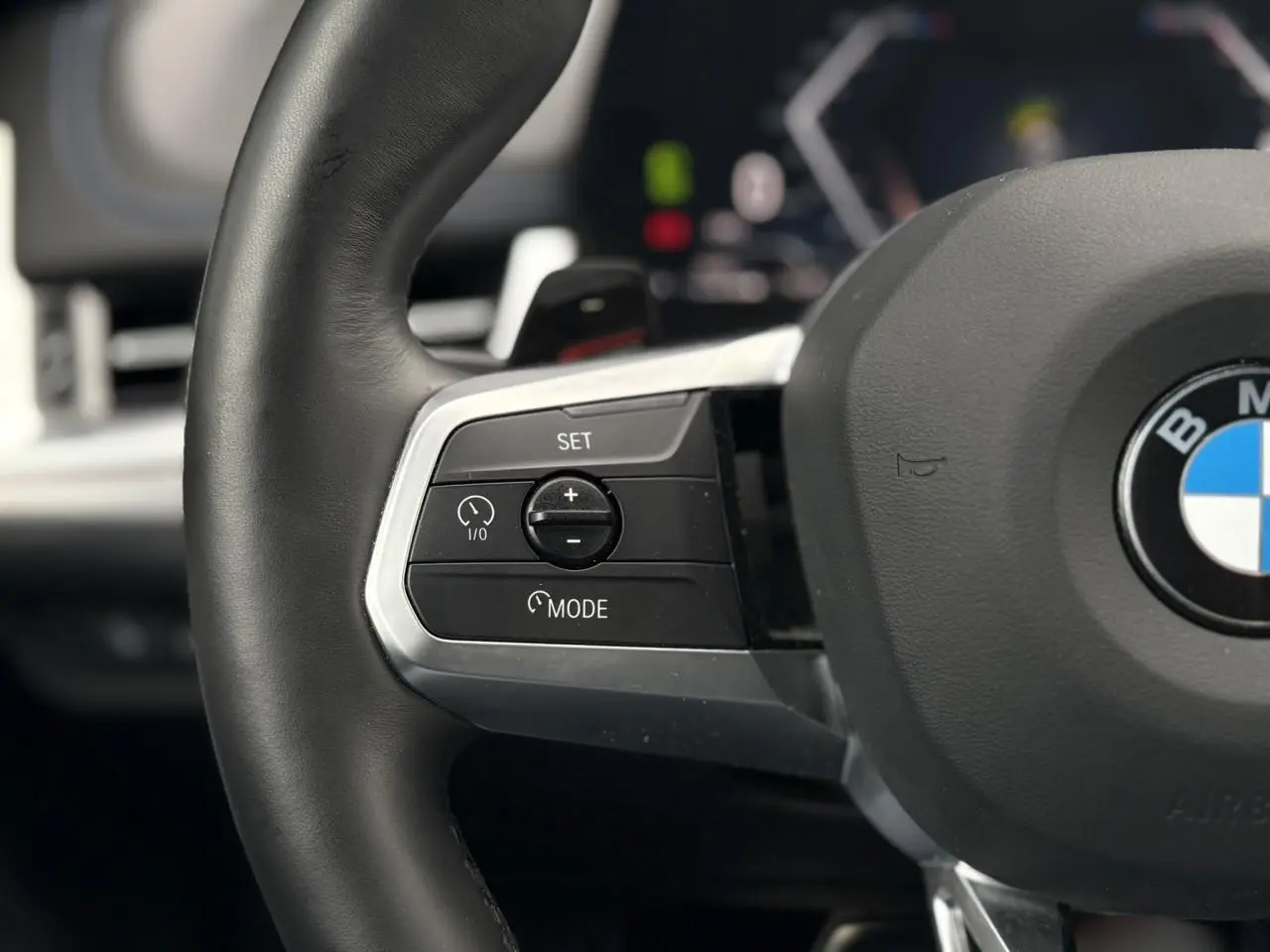 Gros plan sur le côté gauche du volant cuir M de la BMW X1 blanc Mineral avec commandes multifonctions.