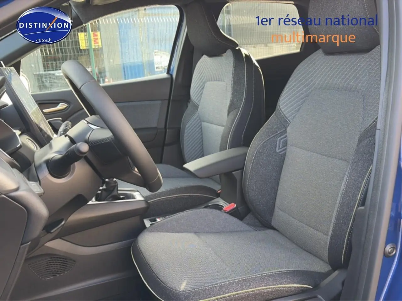 Vue intérieure côté conducteur du Renault Captur Bleu Iron 2025, sièges tissu gris avec accoudoir central.