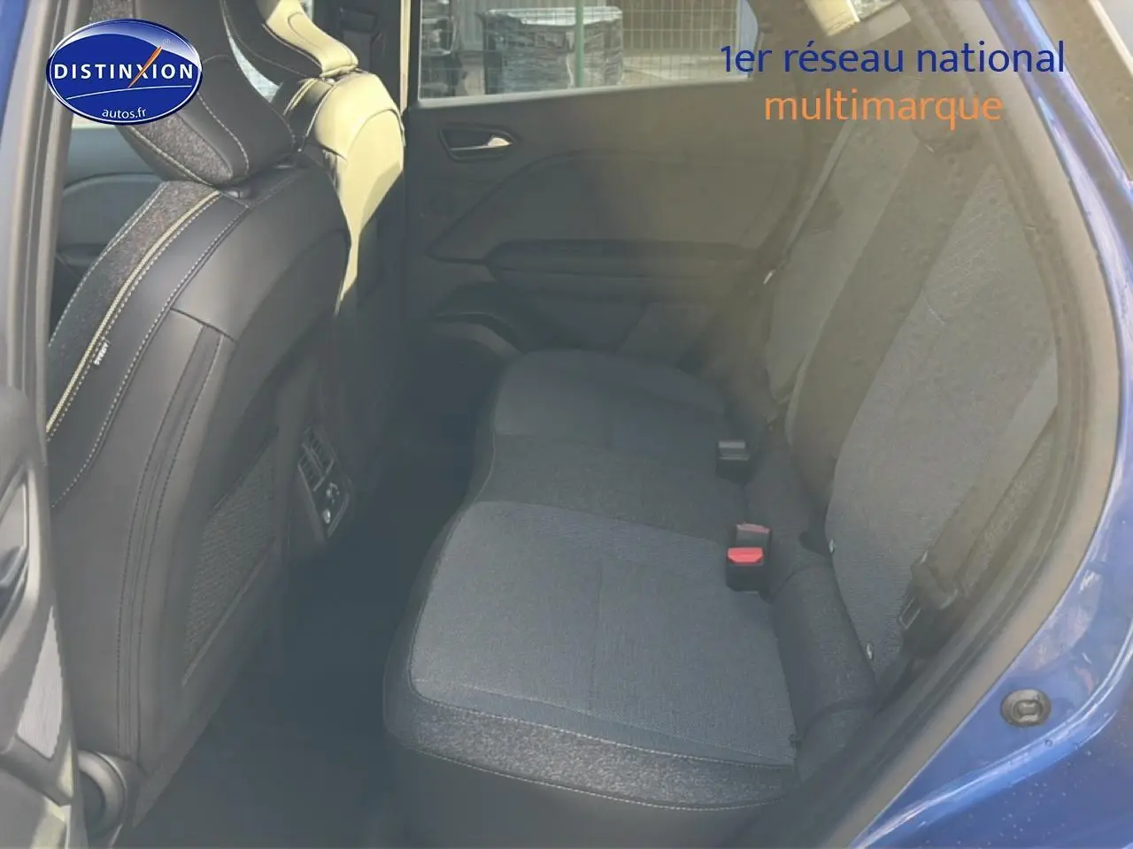 Vue intérieure arrière droite du Renault Captur bleu iron, montrant la banquette tissu et les sièges avant noirs.