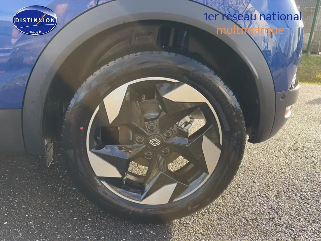 Gros plan sur la roue avant droite d’un Renault Captur Bleu Iron avec jante alu au design géométrique.