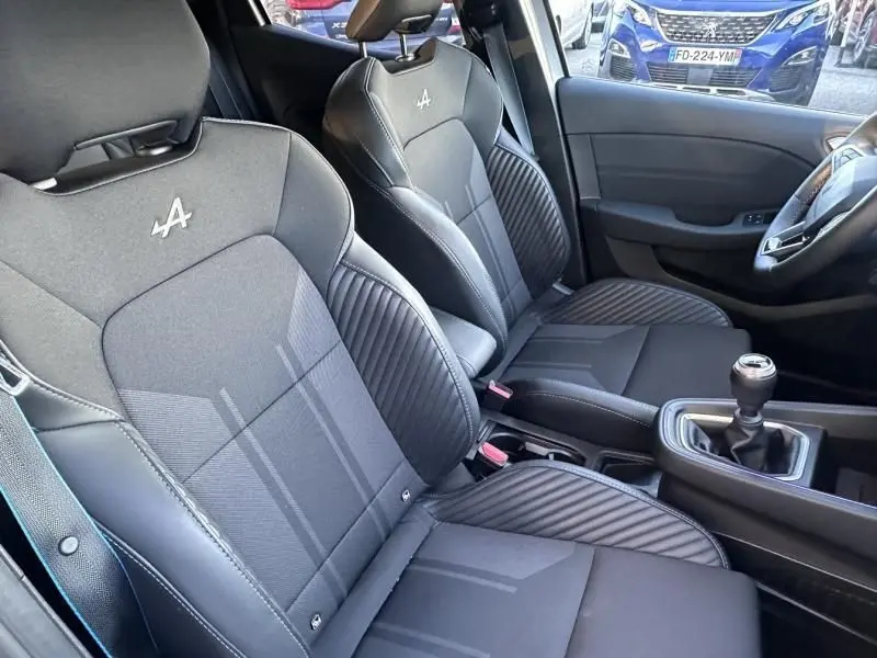 Vue intérieure côté conducteur de la Renault Clio V 1.0 TCE 90 Esprit Alpine 2025, sièges noirs avec logo Alpine brodé.