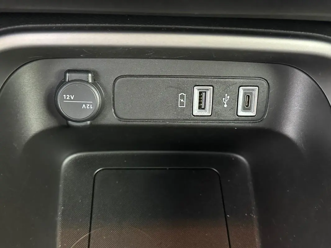 Vue rapprochée des ports USB et prise 12V intégrés dans la console centrale du Jeep Avenger noir 2025.