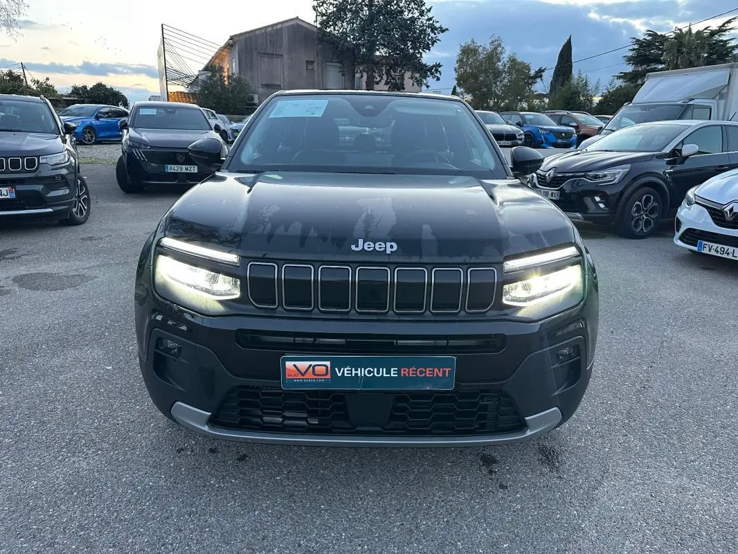 Vue avant frontale du Jeep Avenger noir 2025 avec phares LED allumés et calandre caractéristique à sept fentes.