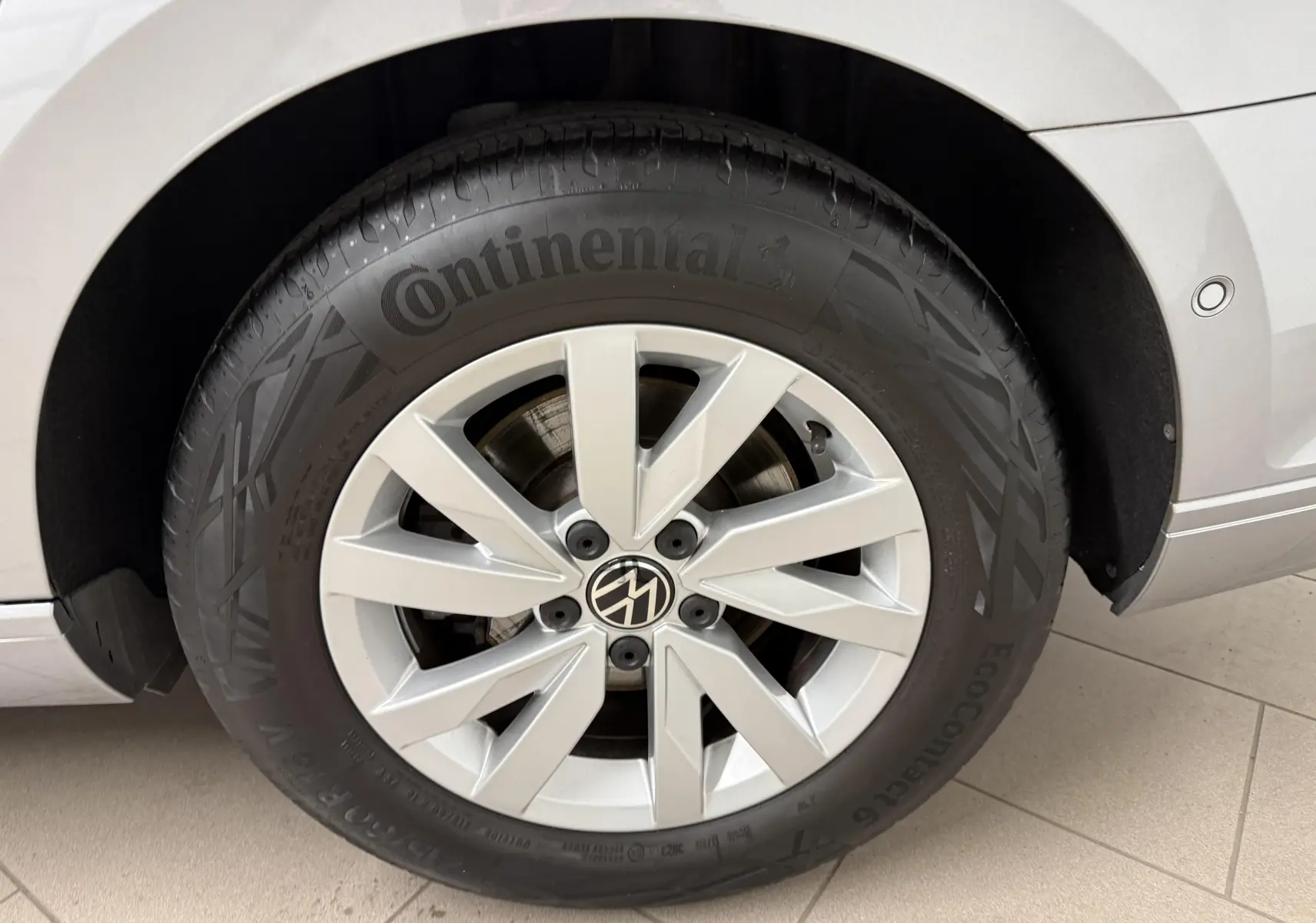 Gros plan sur la roue avant droite d’une Volkswagen Passat SW gris pyrite avec jante alliage et pneu Continental.