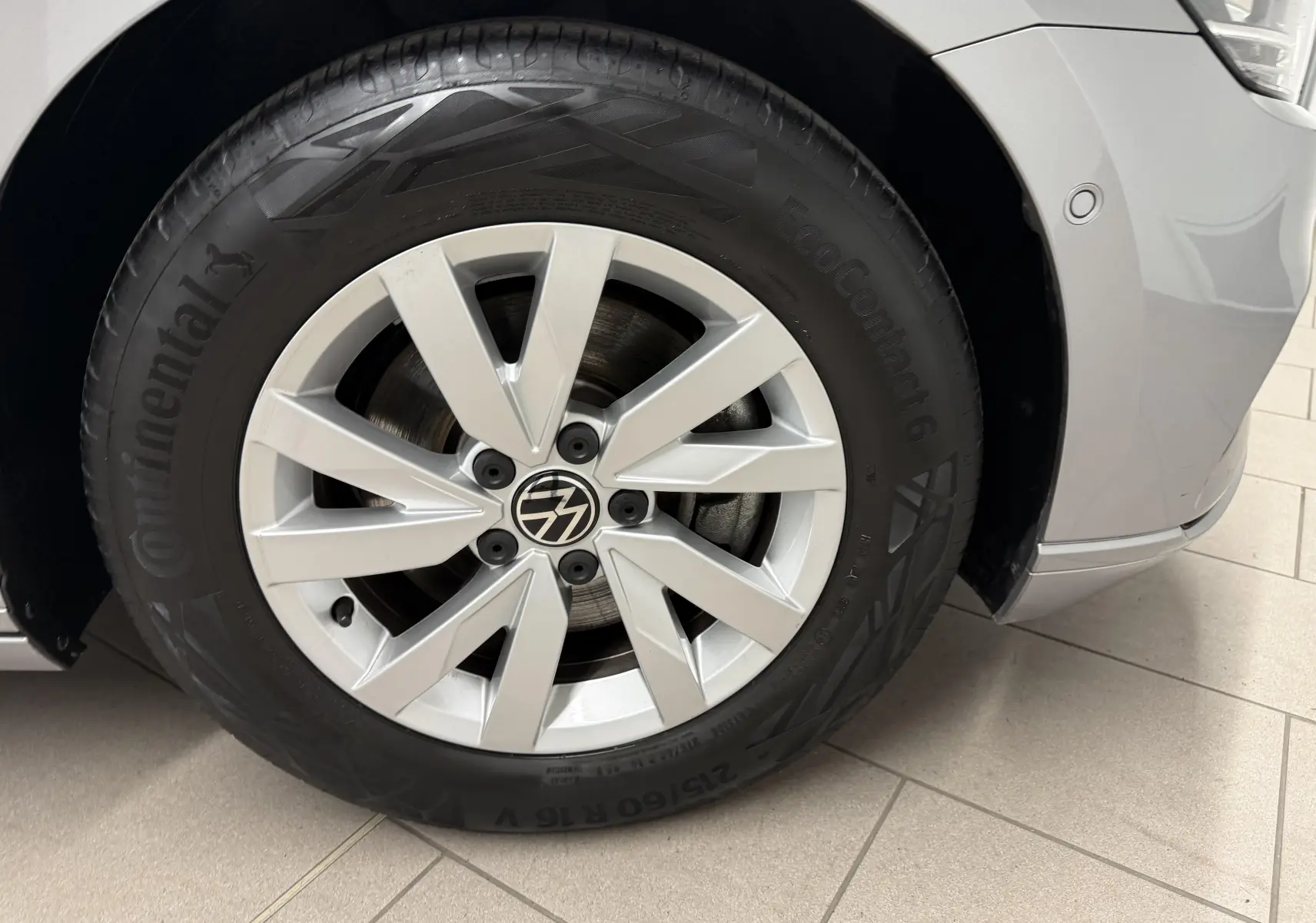 Gros plan sur la roue avant gauche d’une Volkswagen Passat SW 2.0 TDI 122 DSG7 Business gris pyrite, jante alliage 16 pouces.