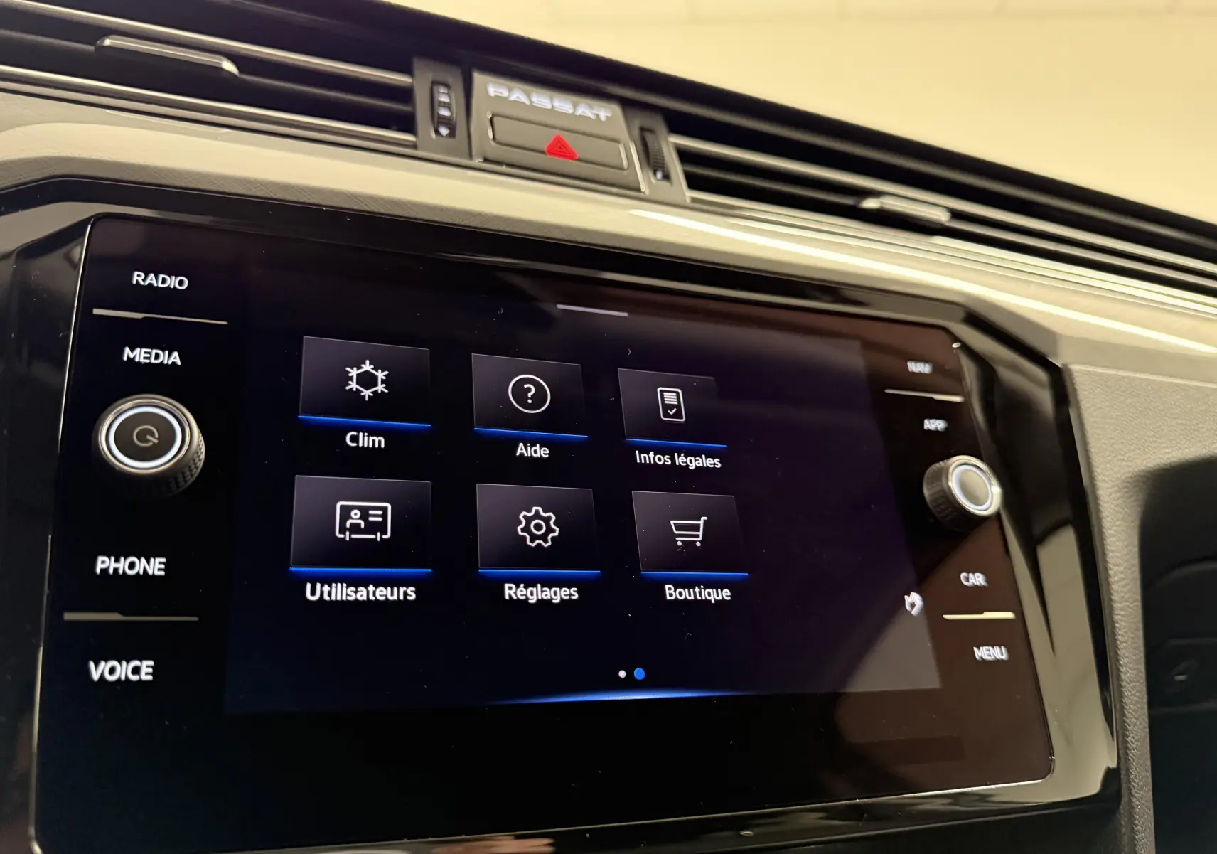 Vue rapprochée de l’écran tactile central de la Volkswagen Passat SW 2024 avec menu des réglages et finition noire brillante.