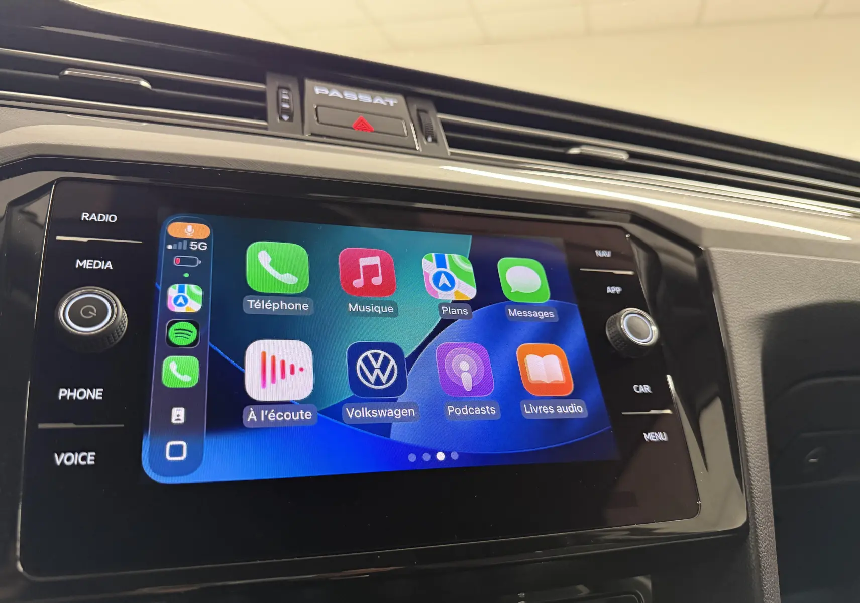 Écran tactile central de la Volkswagen Passat SW 2024 avec interface connectée et commandes autour du tableau de bord noir.