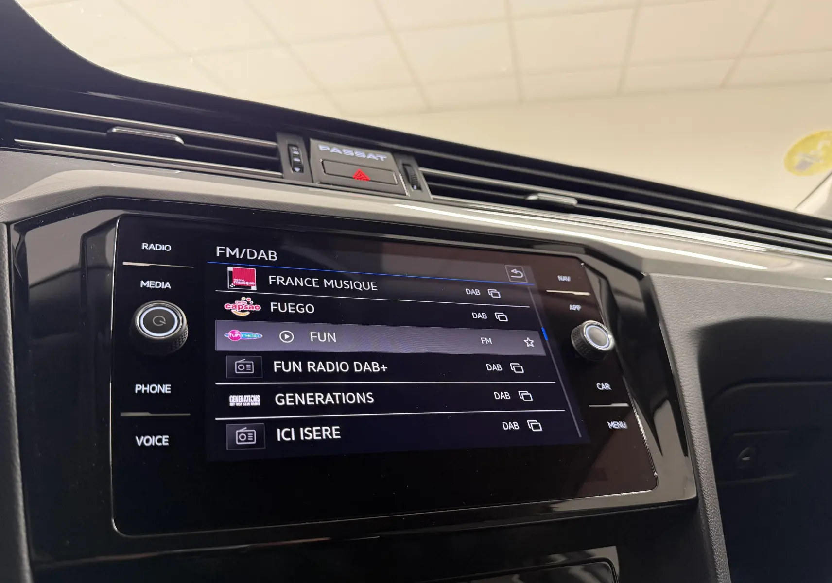 Vue rapprochée de l’écran multimédia de la Volkswagen Passat SW 2024, affichant les stations radio FM/DAB.