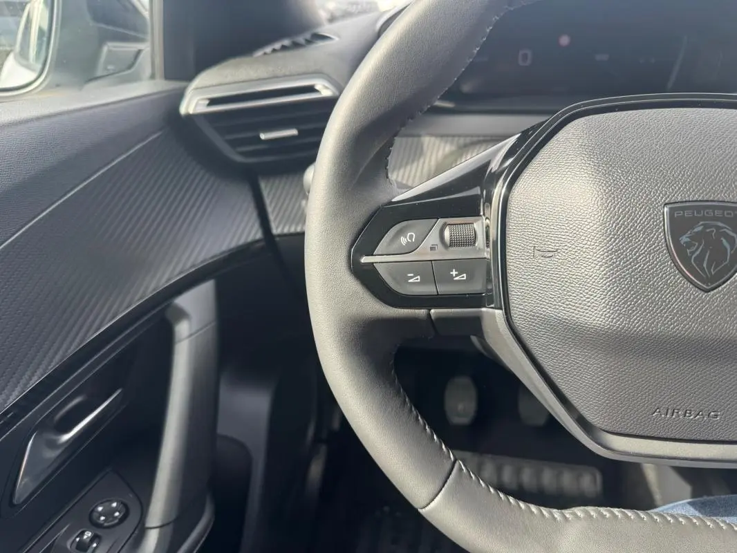 Vue rapprochée du volant et de la portière côté gauche du Peugeot 2008 2024, intérieur noir avec finitions texturées.