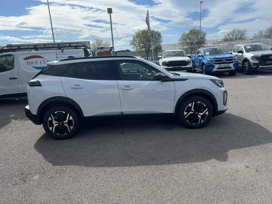 Peugeot 2008 blanc vue de profil côté gauche, avec jantes alliage 17 pouces et barres de toit noires.