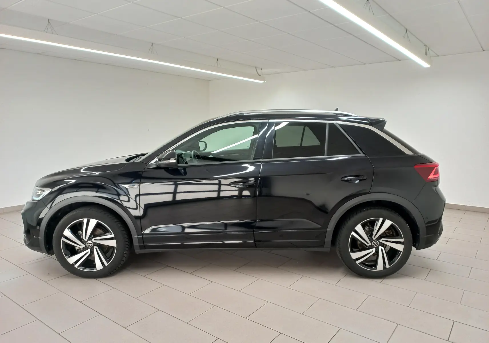 Profil droit du Volkswagen T-Roc 1.5 TSI 150 DSG7 R-Line noir intense nacré, avec jantes alliage distinctives en intérieur neutre.