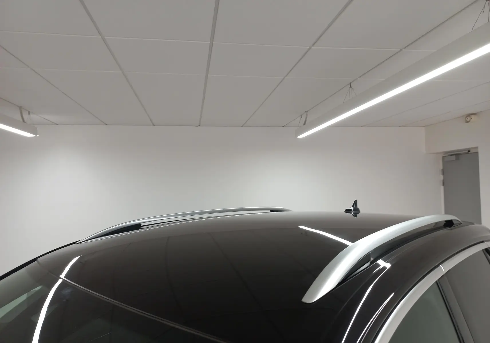 Vue rapprochée du toit noir intense nacré du Volkswagen T-Roc 2025 avec barres de toit argentées en intérieur.