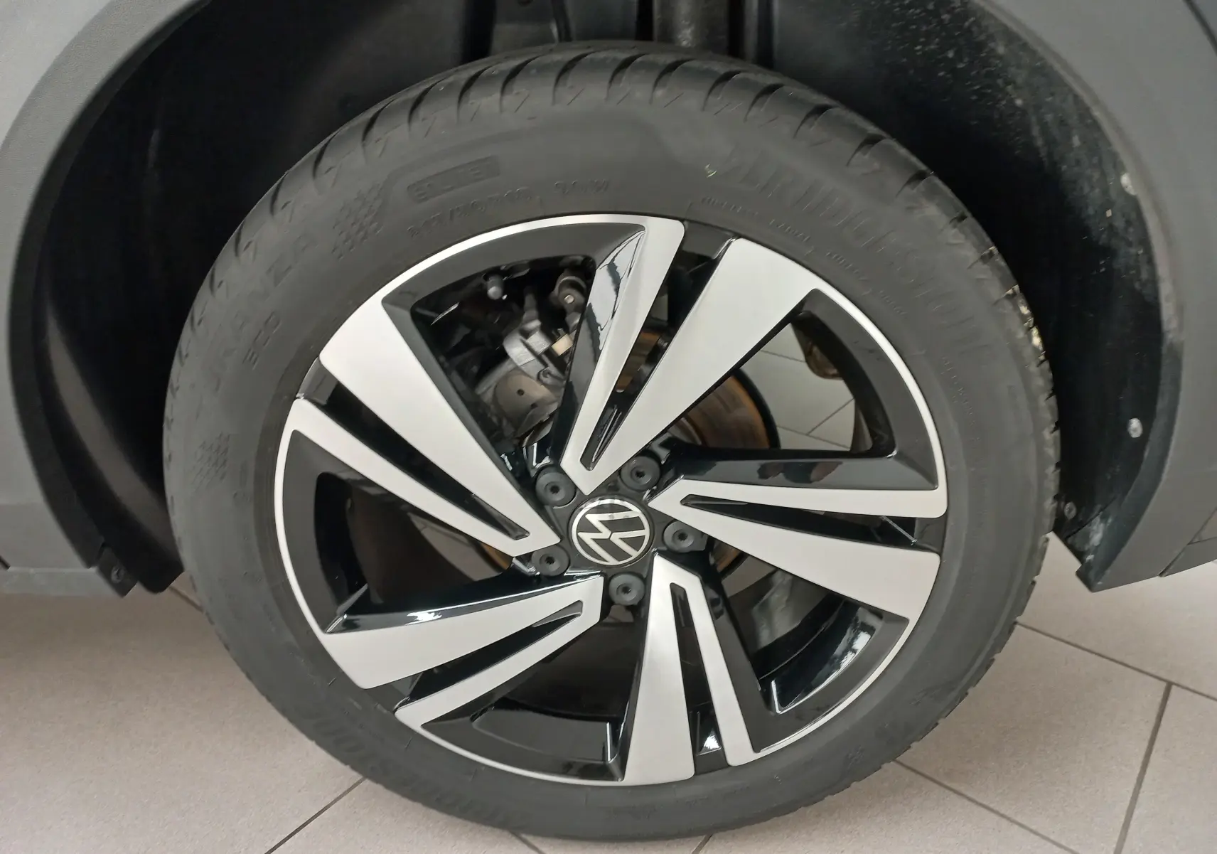 Gros plan sur la roue avant droite du Volkswagen T-Roc 1.5 TSI 150 DSG7 R-Line, jante alliage bicolore noir et argent.