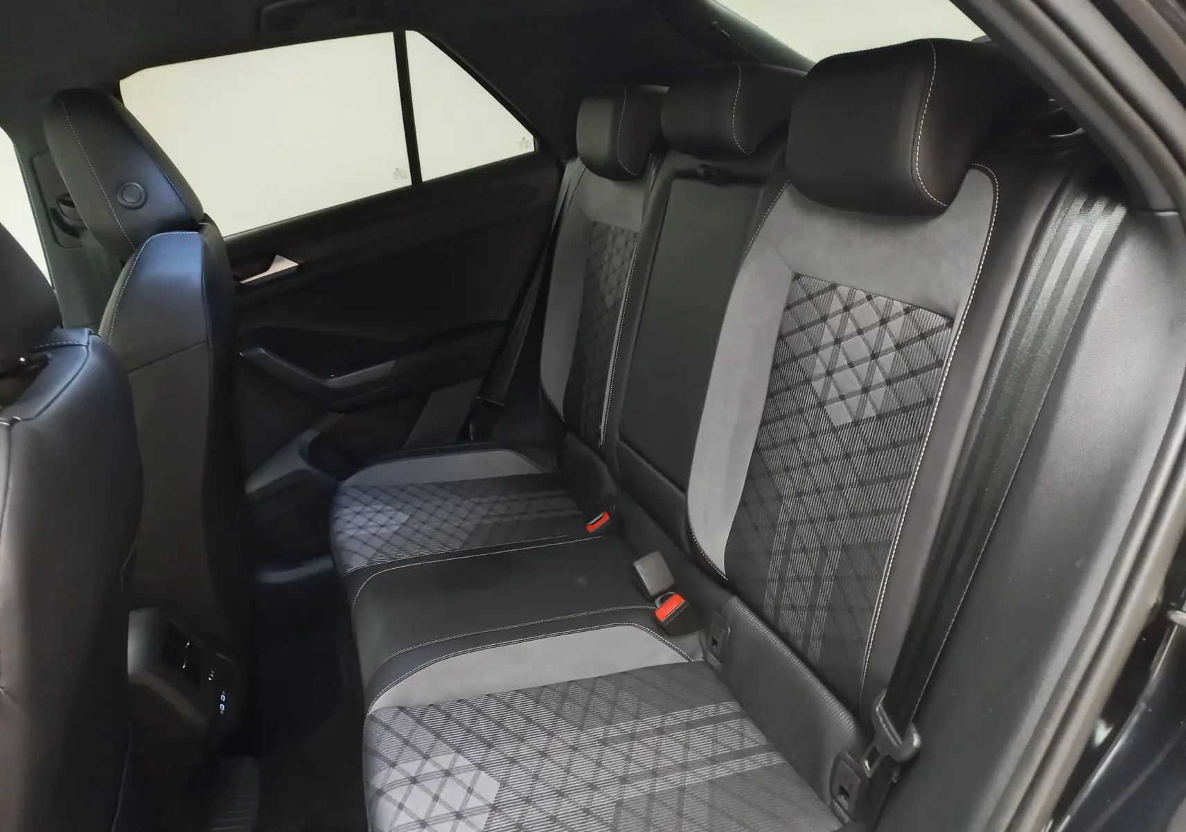 Vue intérieure arrière côté droit du Volkswagen T-Roc 1.5 TSI R-Line 2025, sièges en tissu noir et gris à motifs géométriques.