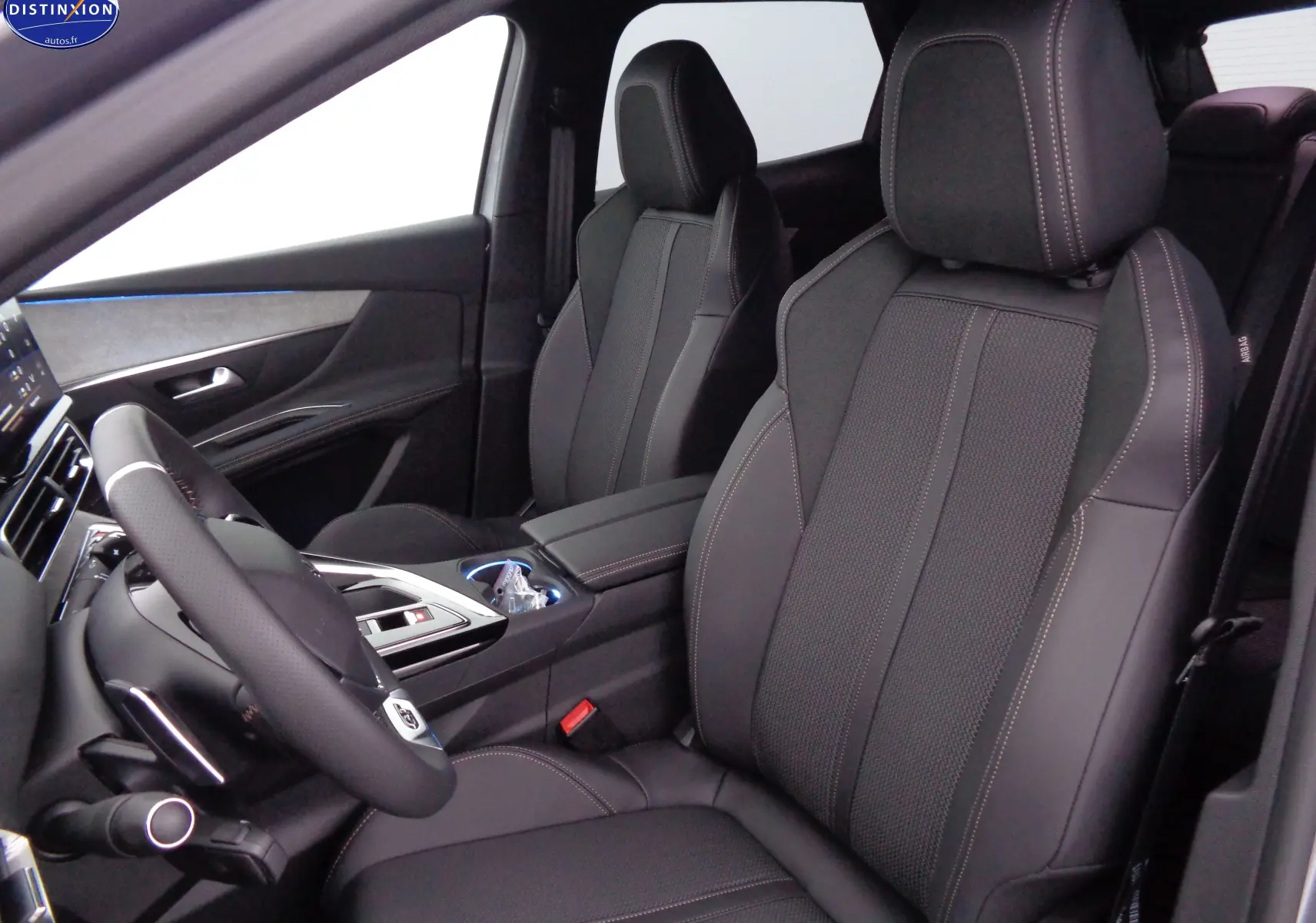 Vue intérieure côté conducteur du Peugeot 3008 2023, sièges en cuir noir avec surpiqûres contrastées et volant sport.