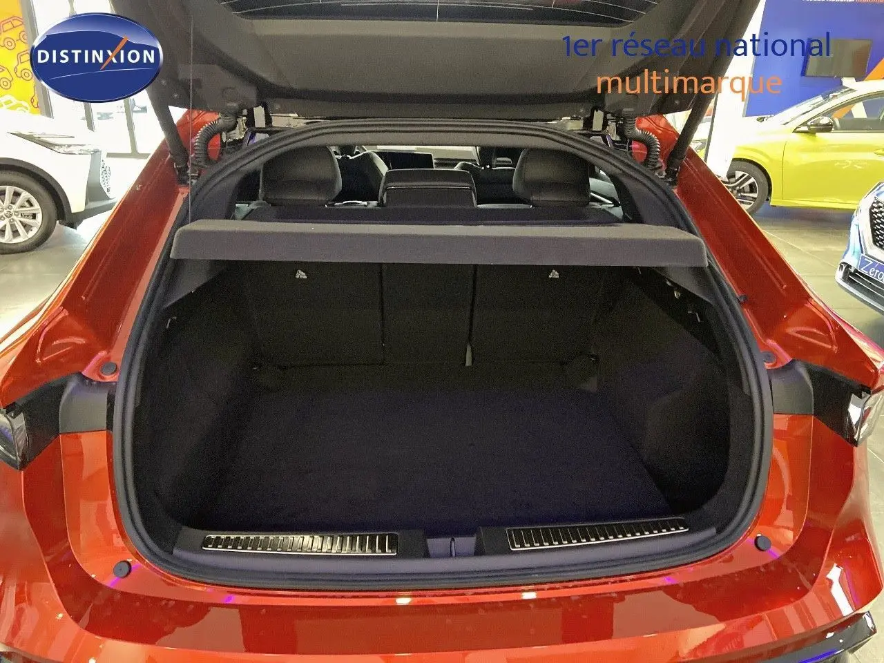 Coffre ouvert vu de l'arrière d'une Renault Rafale 2024 rouge flamme métal, intérieur noir et banquette rabattue.