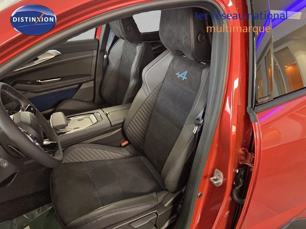 Intérieur côté conducteur d'une Renault Rafale rouge flamme, sièges noirs avec logo Alpine bleu brodé sur appuie-tête.