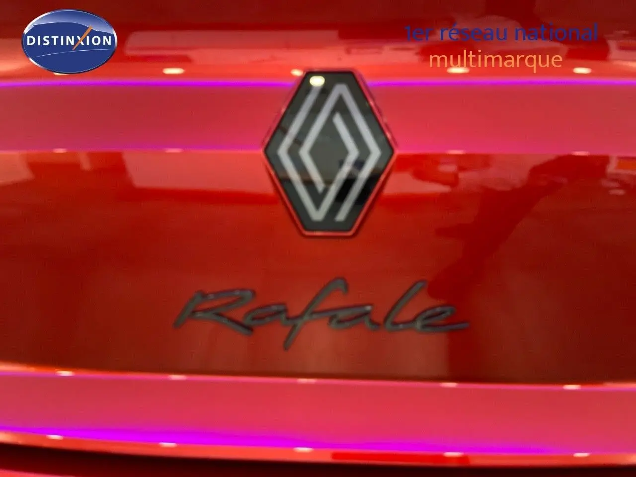 Gros plan sur le logo Renault et l'inscription Rafale sur la malle arrière rouge flamme métal du véhicule.