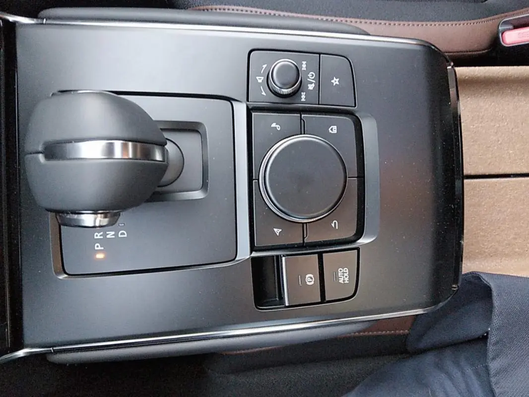 Vue plongeante sur la console centrale grise du Mazda MX-30 électrique 2021, avec levier de vitesses et commandes multimédia.