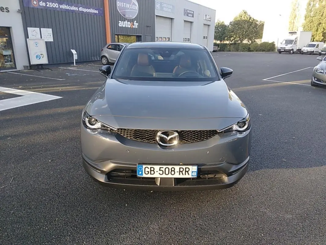 Vue frontale d'un Mazda MX-30 gris électrique 2021 avec calandre noire et plaques d'immatriculation françaises visibles.