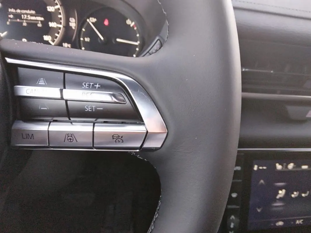 Gros plan sur les commandes au volant gris du Mazda MX-30 électrique, mettant en valeur les boutons de régulateur de vitesse.