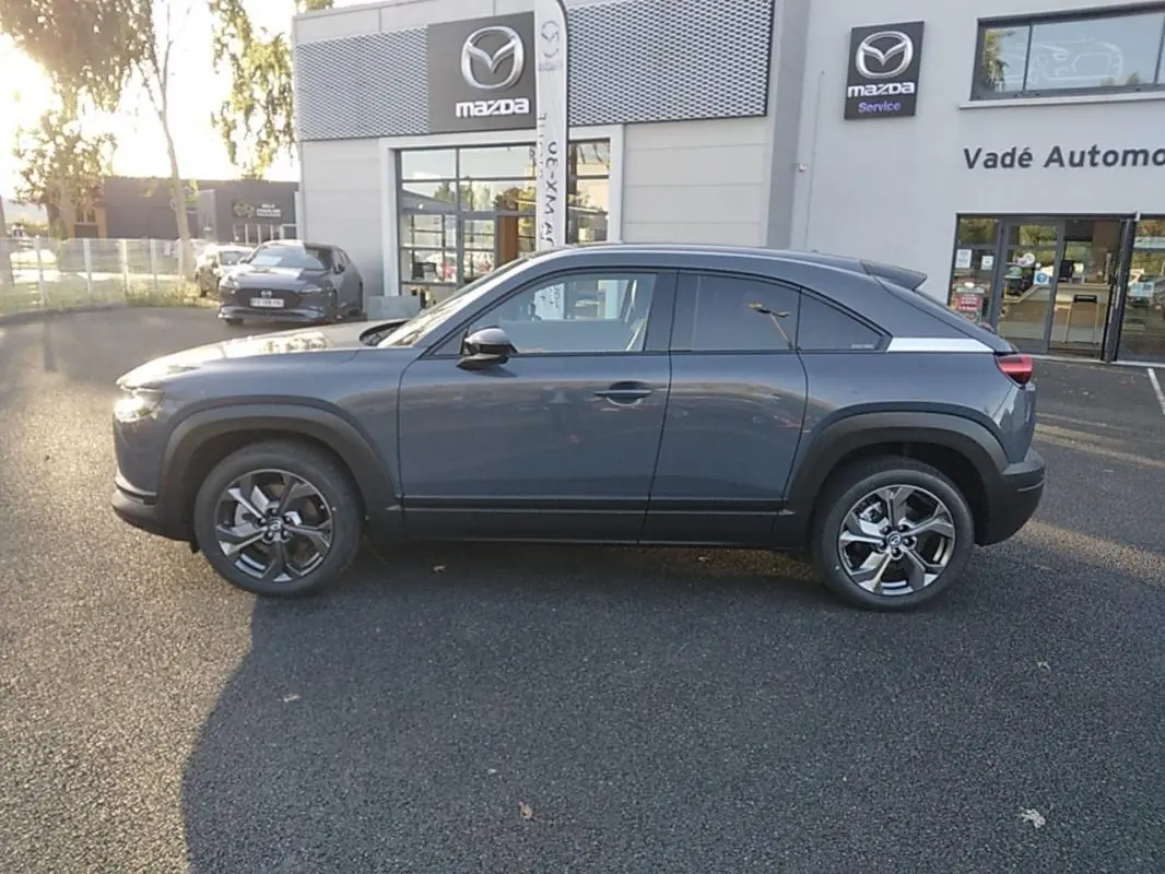 Vue de profil côté gauche d'un Mazda MX-30 gris électrique 2021, avec jantes alliage et toit légèrement incliné.