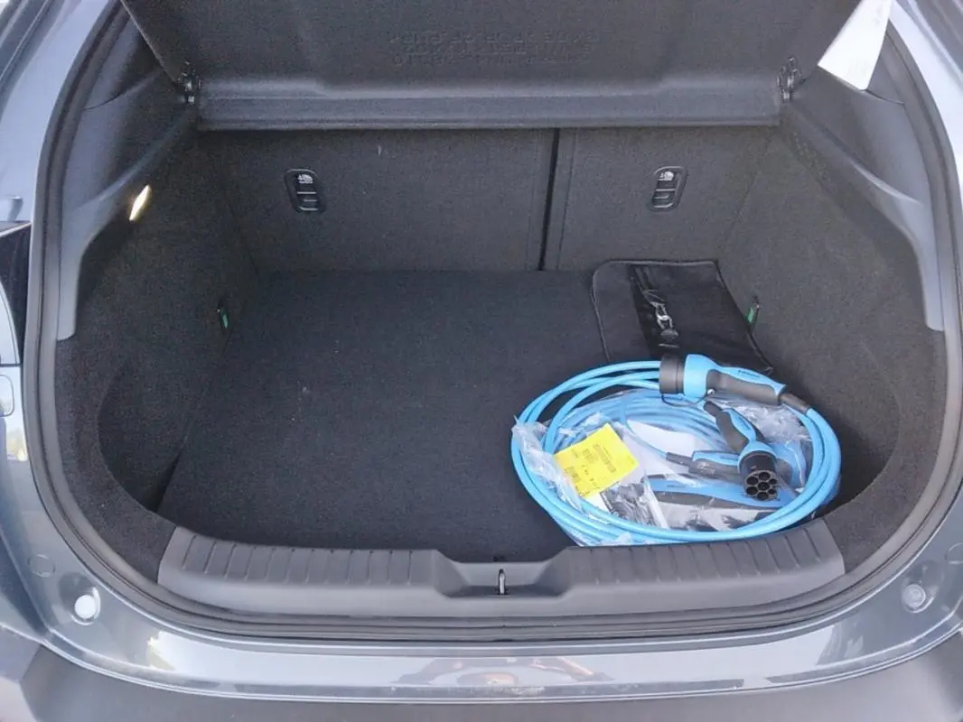 Coffre ouvert d'une Mazda MX-30 gris 2021, avec câble de recharge électrique bleu visible à l'intérieur.