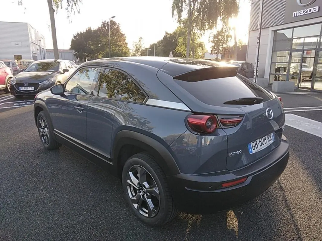 Vue 3/4 arrière droite d'un Mazda MX-30 gris électrique 2021 avec vitres teintées et jantes distinctives.