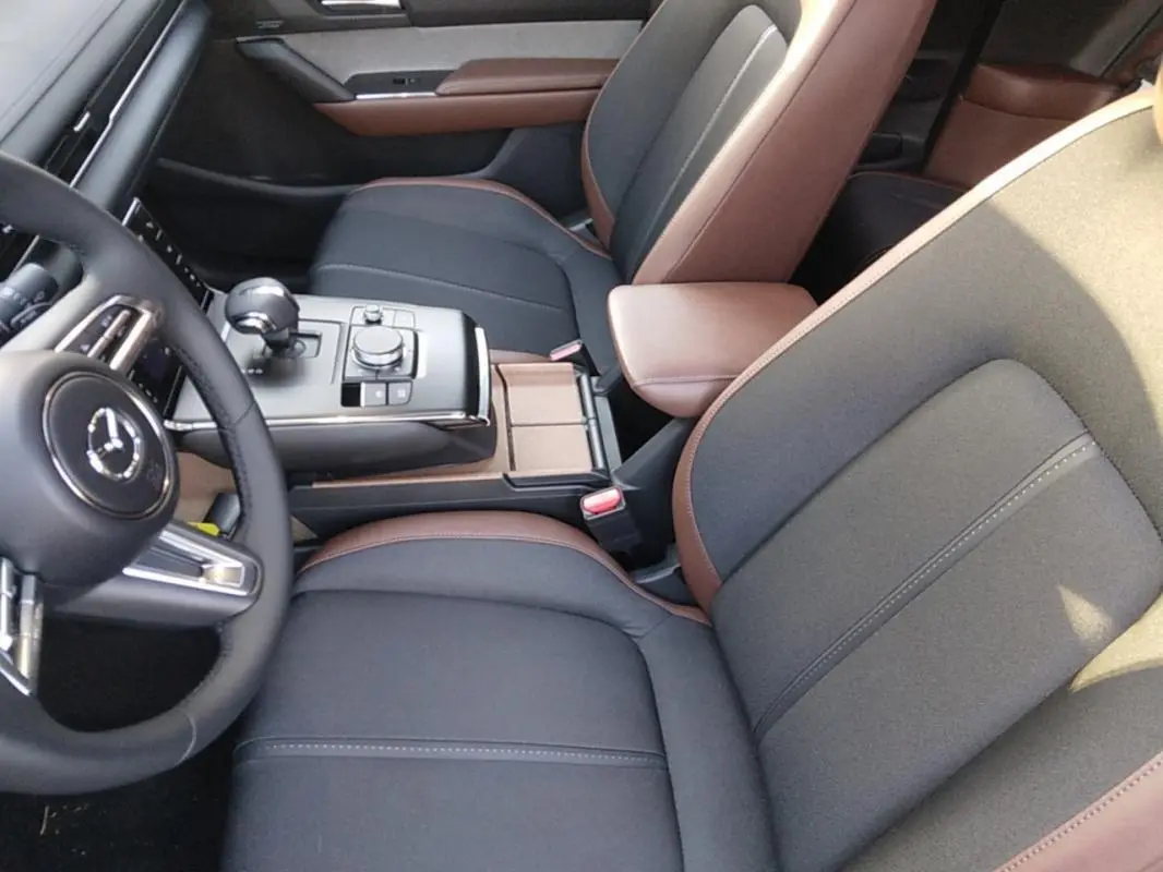 Vue intérieure rapprochée du Mazda MX-30 2021 gris, montrant sièges bi-matière noirs et marron avec console centrale moderne.