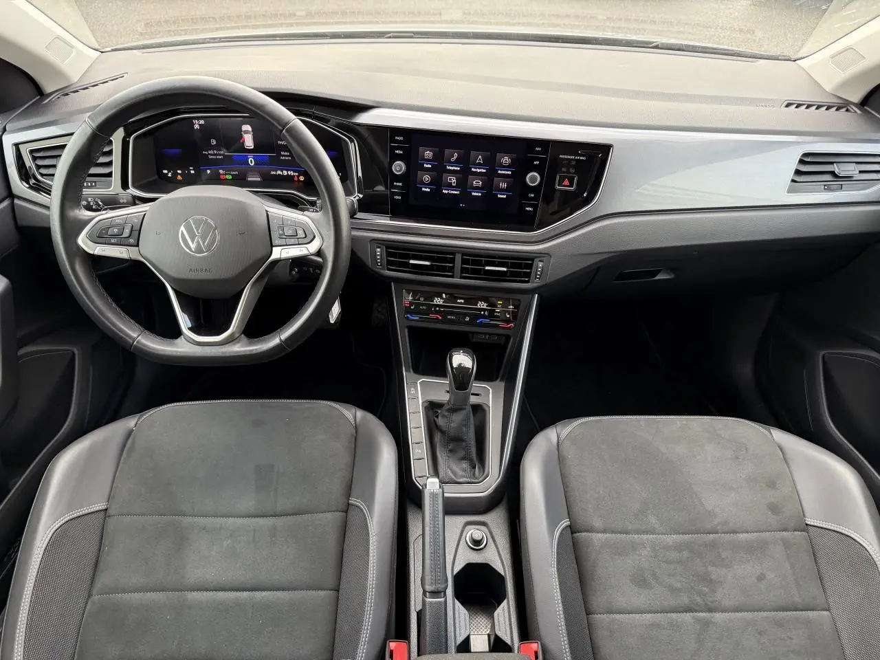 Intérieur avant de la Volkswagen Polo 2025 avec tableau de bord moderne, volant cuir multifonction et sellerie microfleece noire.