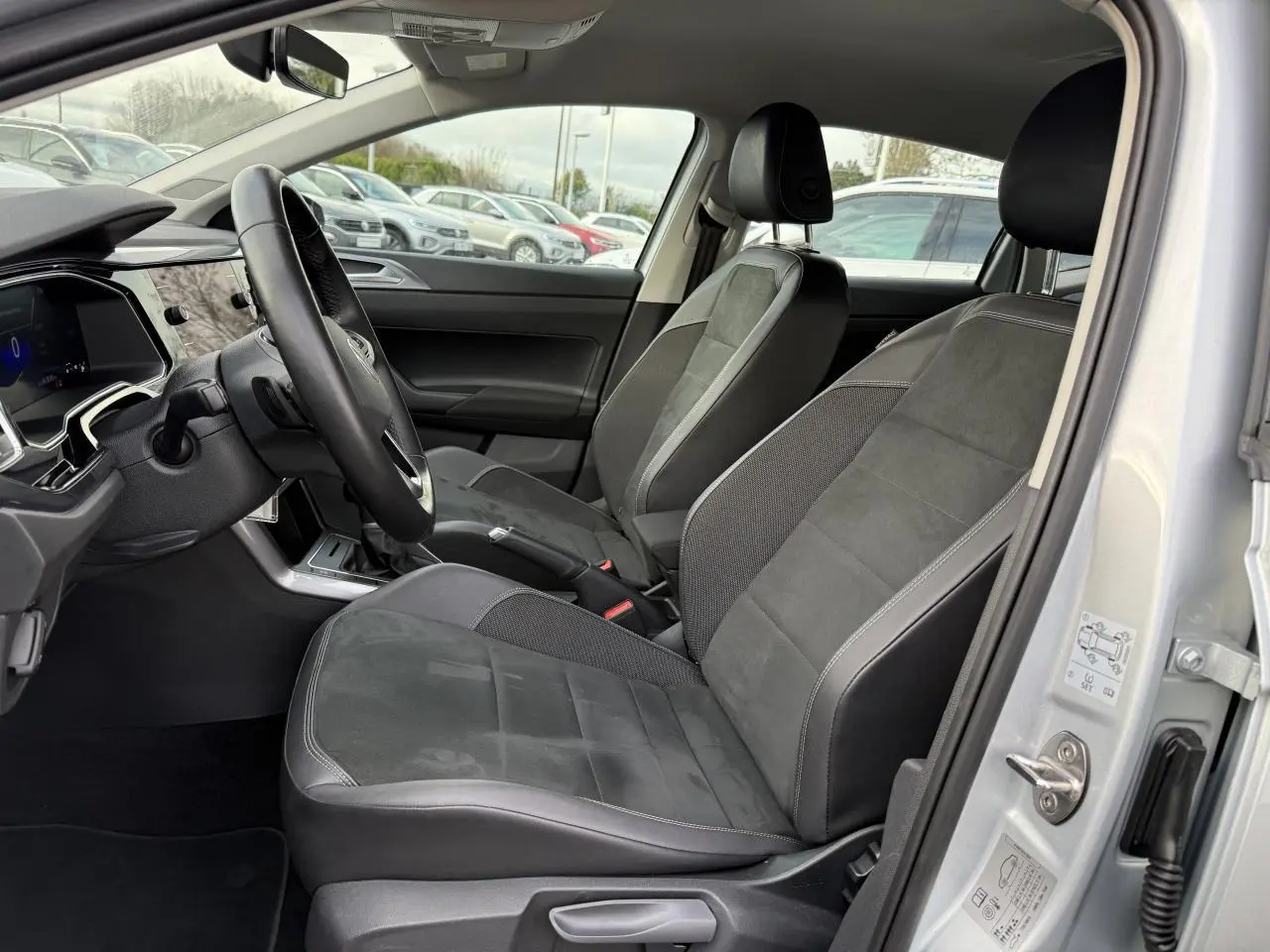 Vue intérieure côté conducteur de la Volkswagen Polo 2025 argent, sièges Microfleece ArtVelours noirs et tableau de bord moderne.