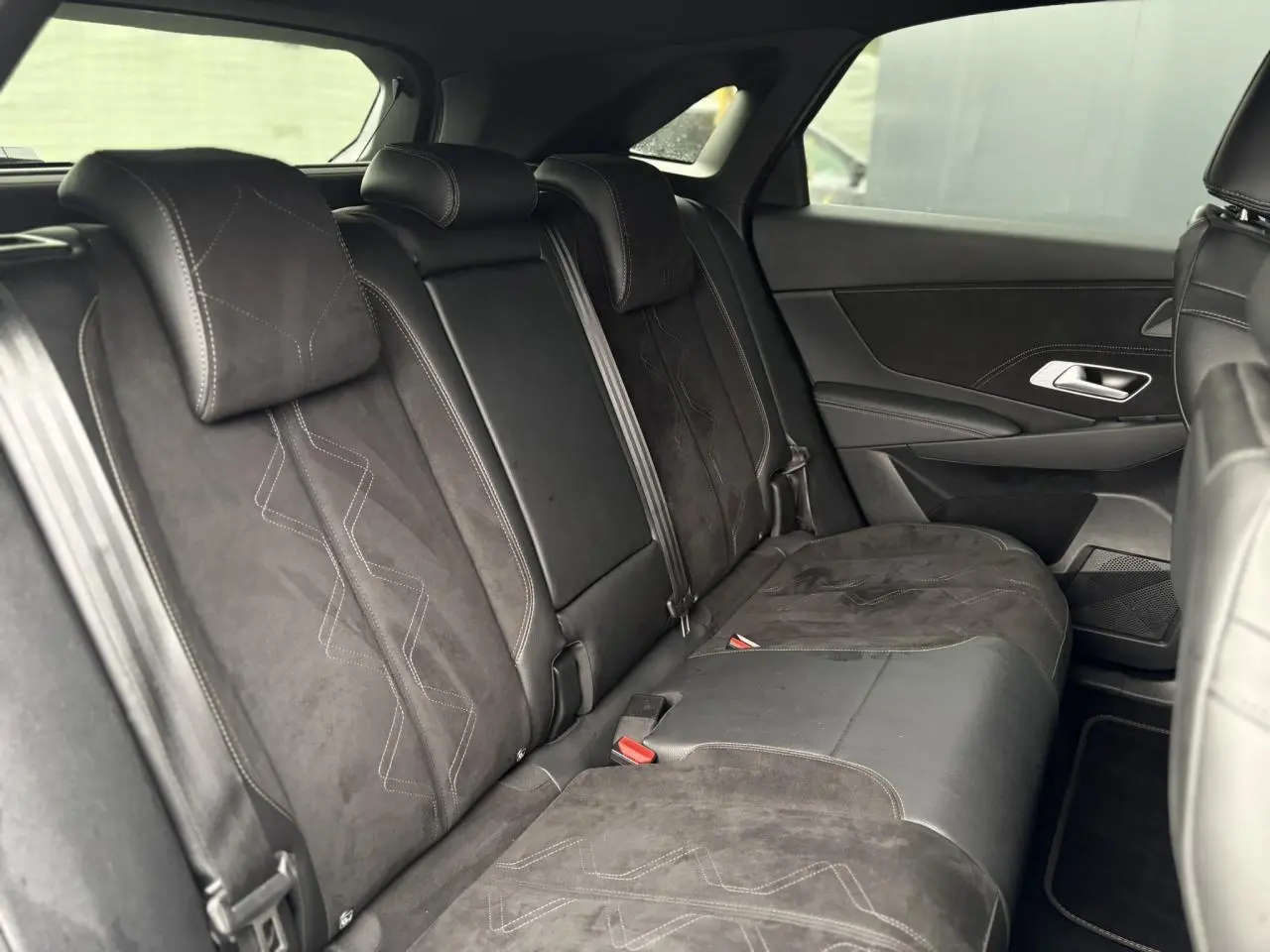 Vue de côté droit de la banquette arrière en Alcantara noir profond du DS7 1.6 E-Tense 225 gris laqué, avec surpiqûres visibles.