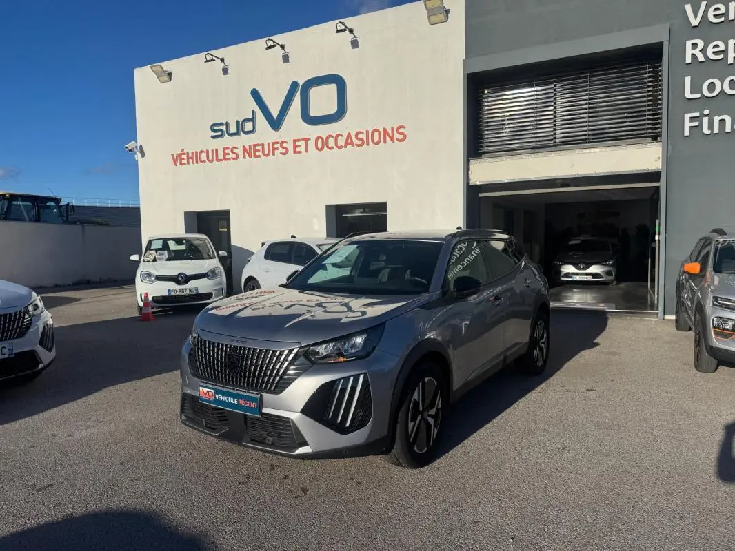 Peugeot 2008 Hybrid gris en 3/4 avant droit, avec barres de toit et jantes alliage 17 pouces visibles.