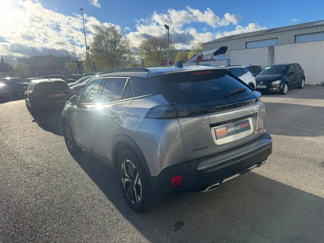 Peugeot 2008 Hybrid gris en 3/4 arrière droit, avec barres de toit et jantes alliage 17 pouces visibles.