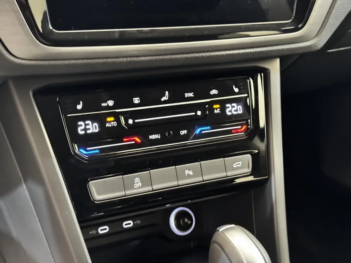 Gros plan sur la console centrale du Volkswagen Touran 2024, avec commandes climatisation digitale et levier de boîte automatique.