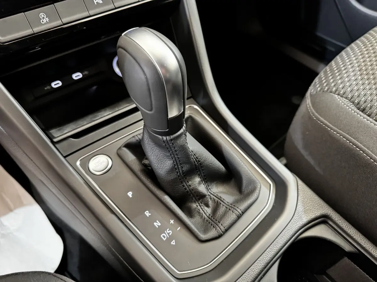 Gros plan sur la console centrale du Volkswagen Touran 2024, montrant le levier de vitesse automatique en cuir noir.