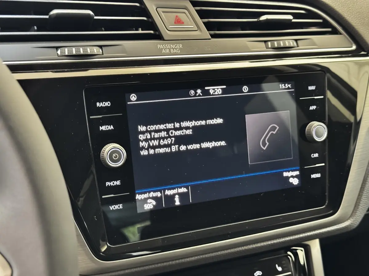 Vue rapprochée de l’écran tactile central noir du tableau de bord du Volkswagen Touran 2024, affichant un message d’appairage téléphone.