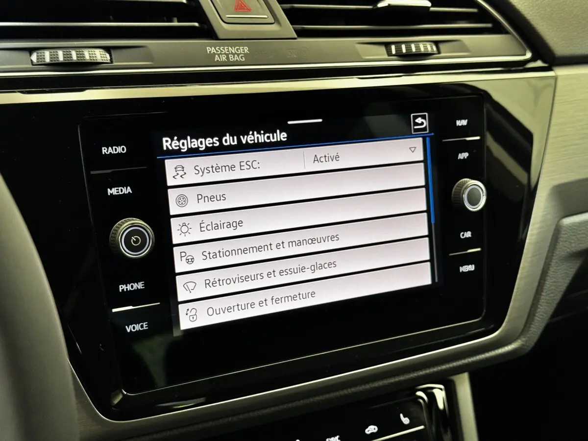 Vue rapprochée de l'écran tactile central noir affichant les réglages du véhicule dans l'habitacle du Volkswagen Touran 2024.