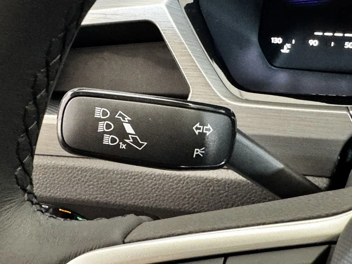 Gros plan sur la manette de commande des phares et clignotants du Volkswagen Touran 2024, intérieur gris.