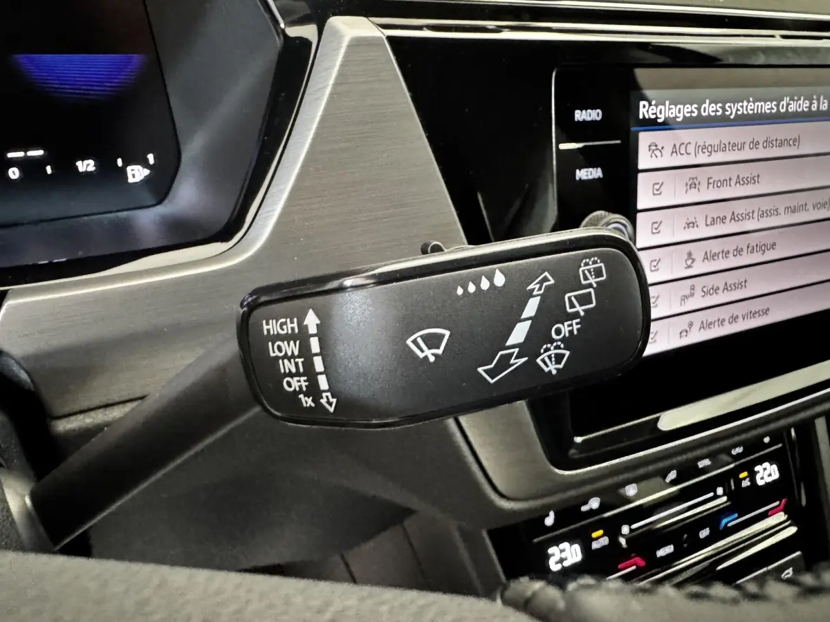 Gros plan sur la commande des essuie-glaces du Volkswagen Touran 2024, avec écran tactile et tableau de bord digital.